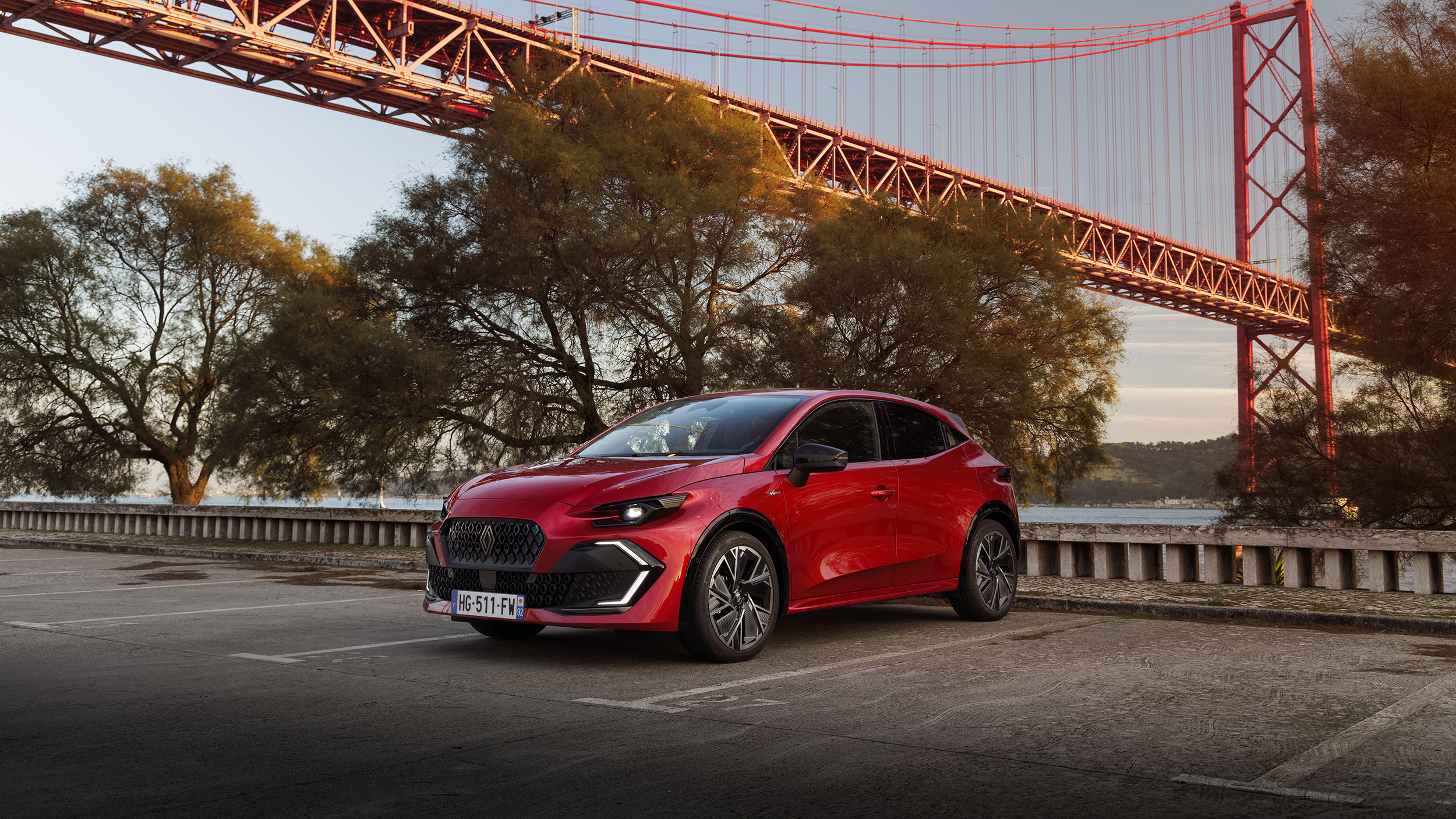 Ein roter Renault Clio steht an der Küste nahe einer Brücke.