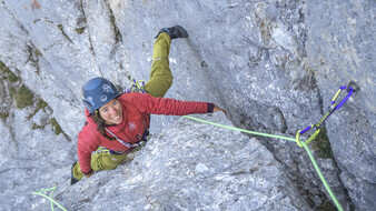 Eine Frau klettert auf Felsen und ist angeleint.