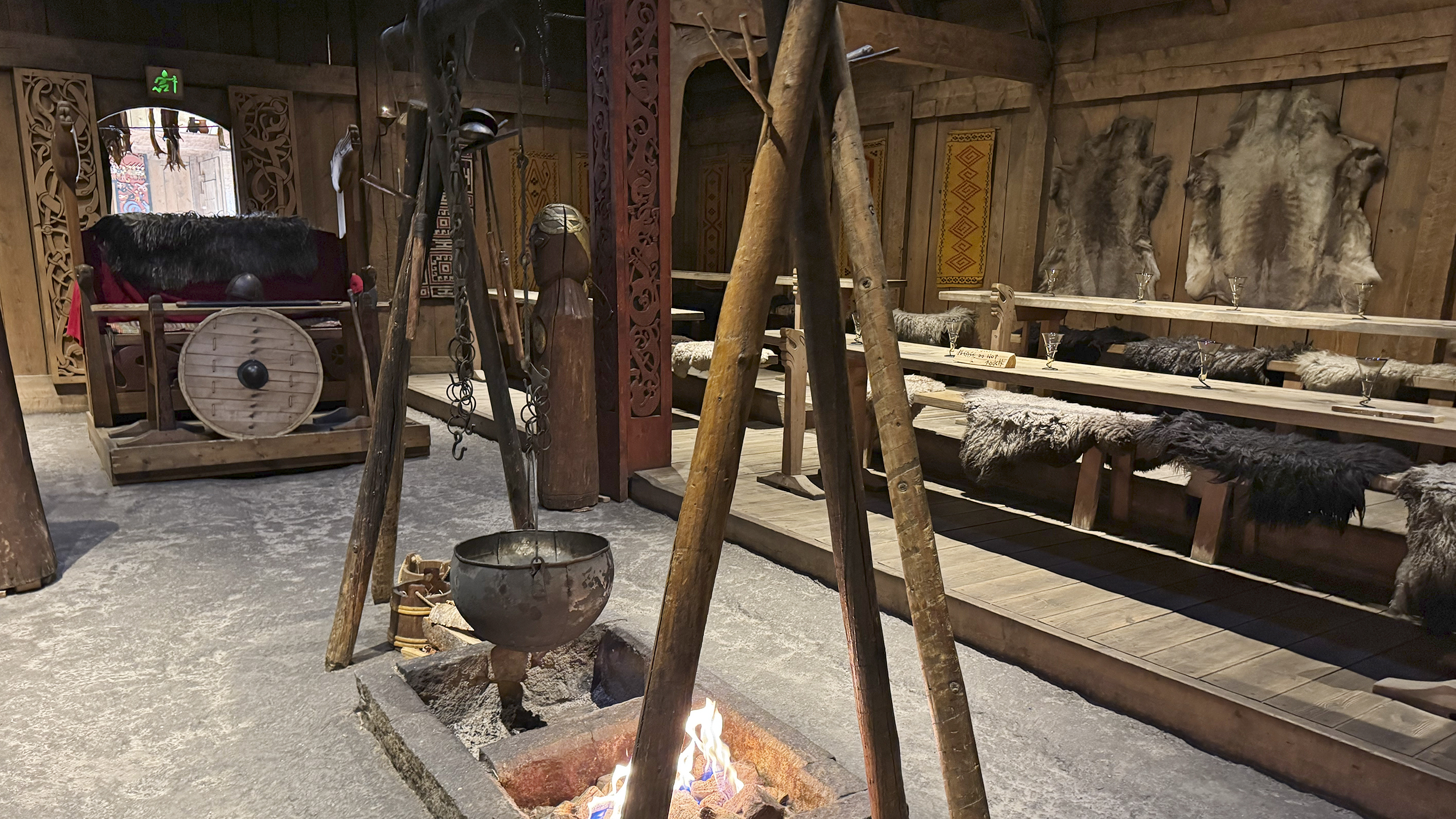 Eine Feuerstelle und ein langer Holztisch im Langhaus der Nordmänner.