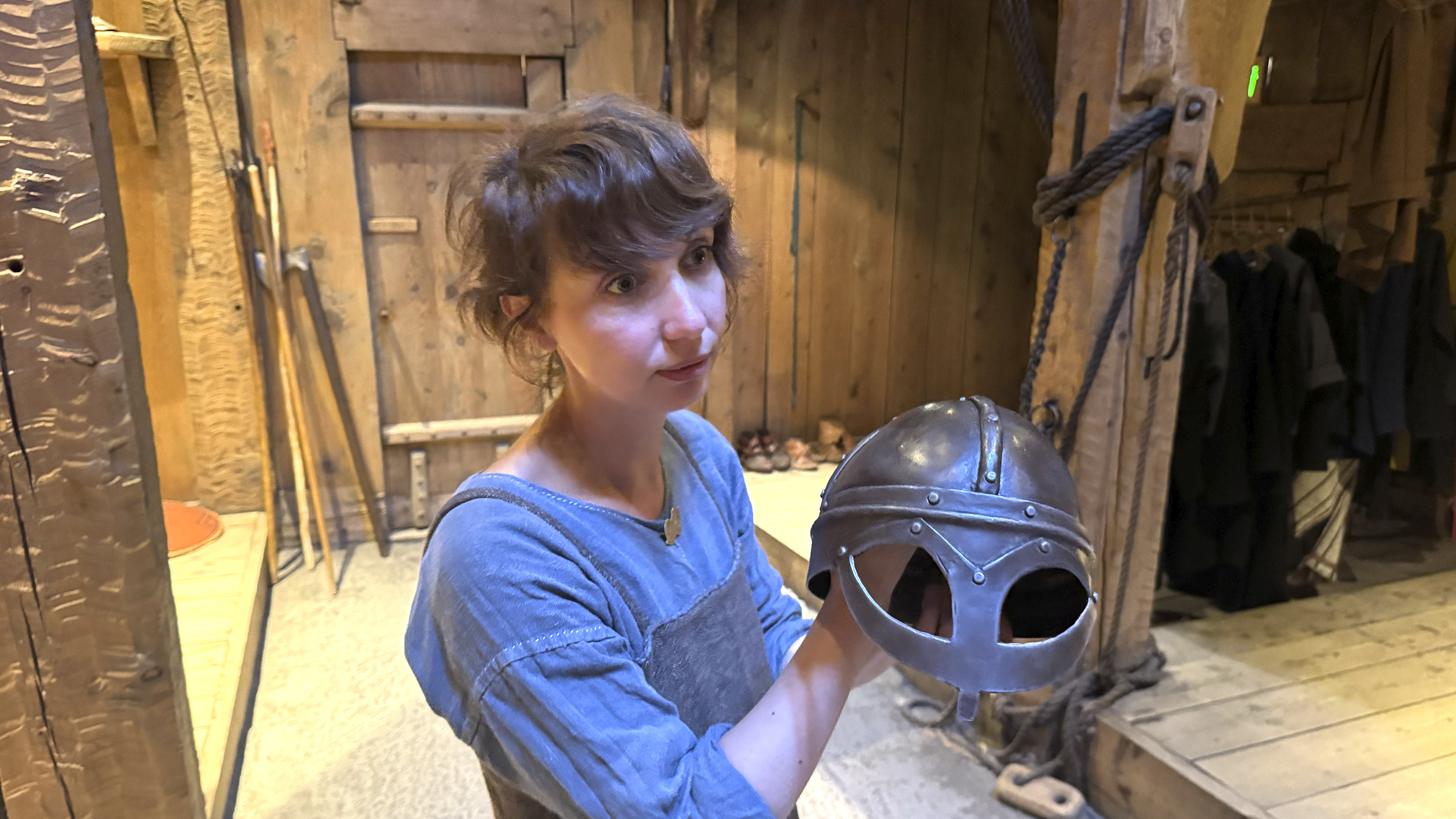 Eine Fremdenführerin zeigt einen Helm im Langhaus der Nordmänner.