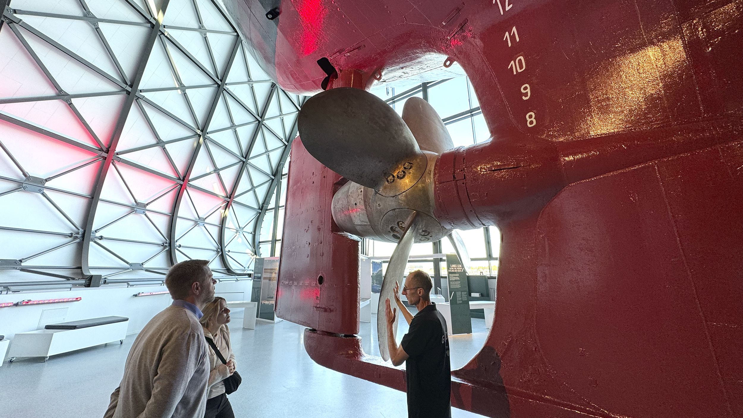 Museum: Drei Menschen stehen bei der großen Schiffsschraube.