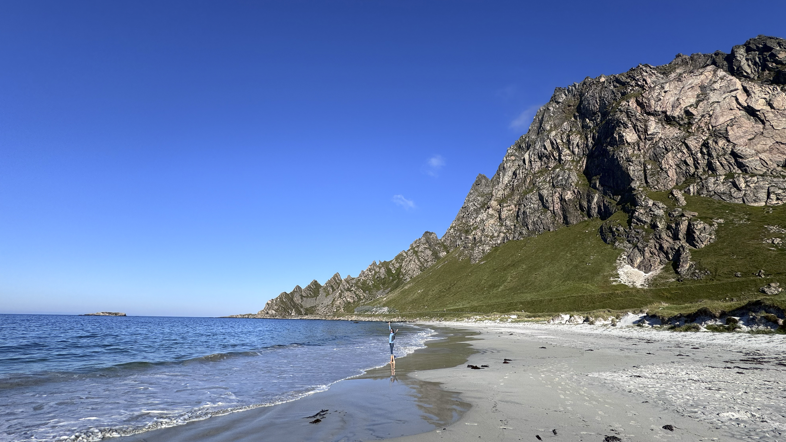 Küstenlandschaft mit Bergen und weißem Sandstrand.