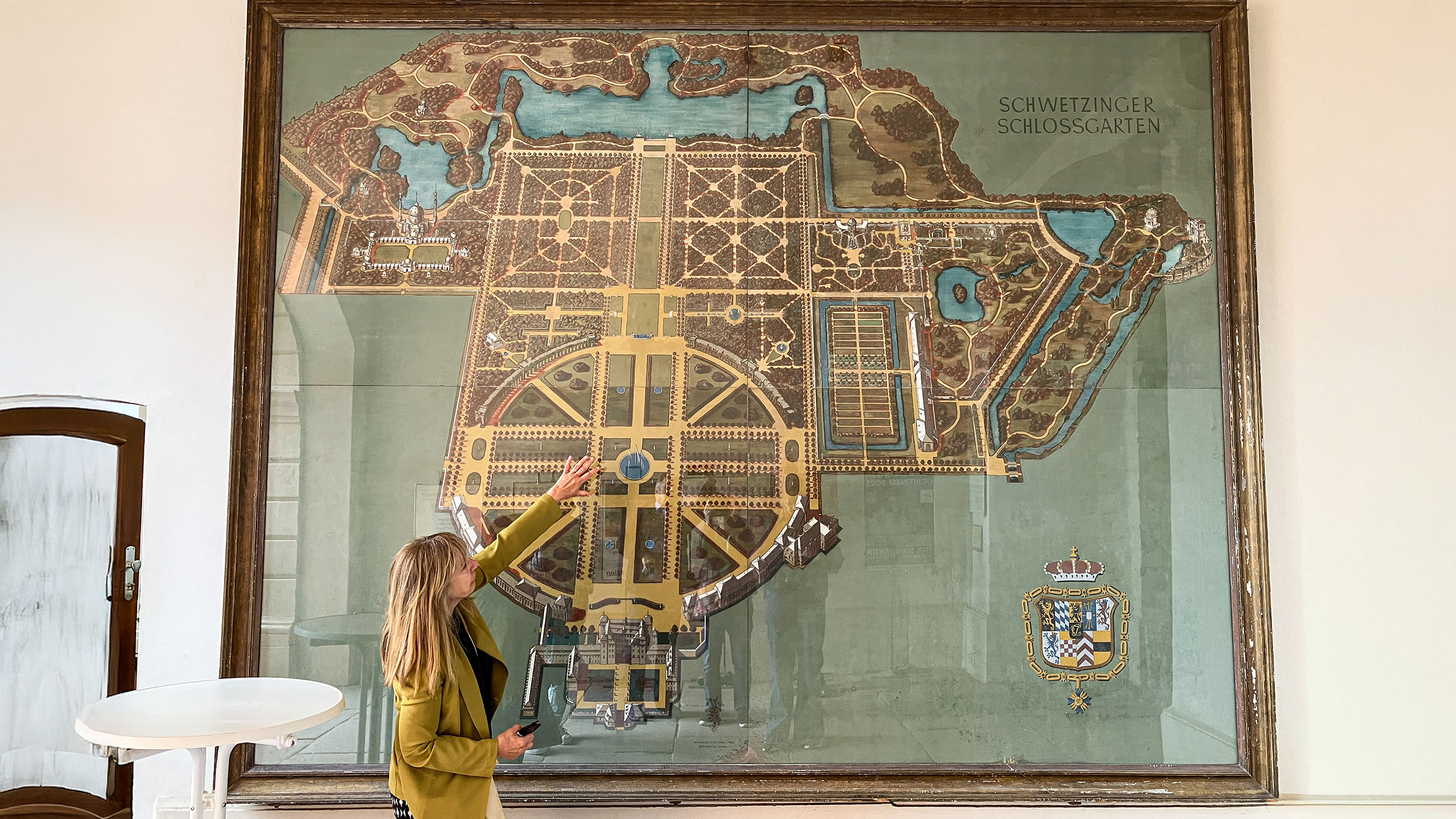REiseleiterin vor einem übergroßen Plan des Barock-Schlossgartens in Schwetzingen