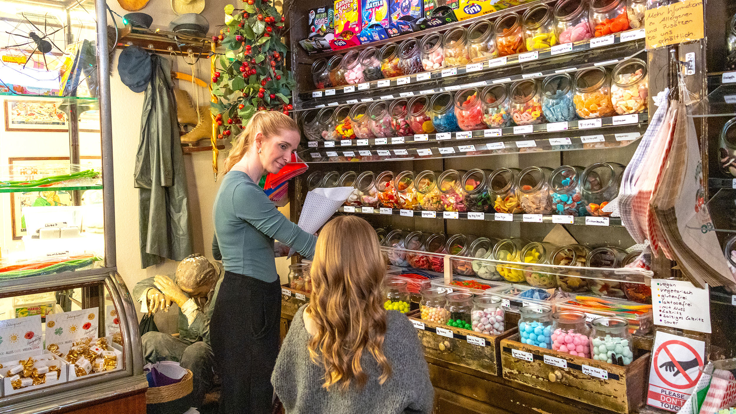 Verkäuferin füllt für ein Kind ein Papierstanitzel mit Süßigkeiten im Heidelberger Zuckerladen