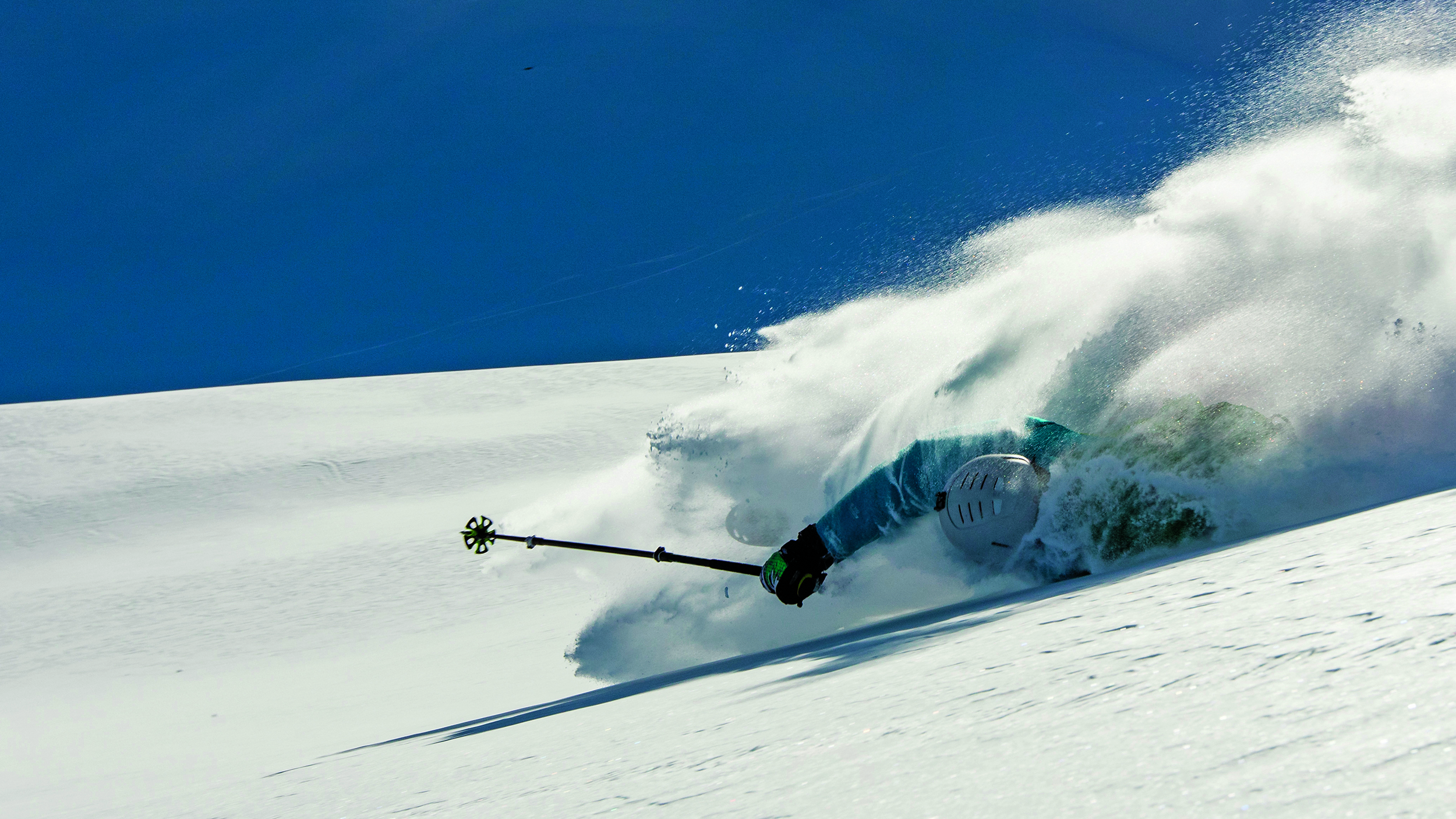Skifahrer stürzt bei der Abfahrt auf einem verschneiten Berghang.