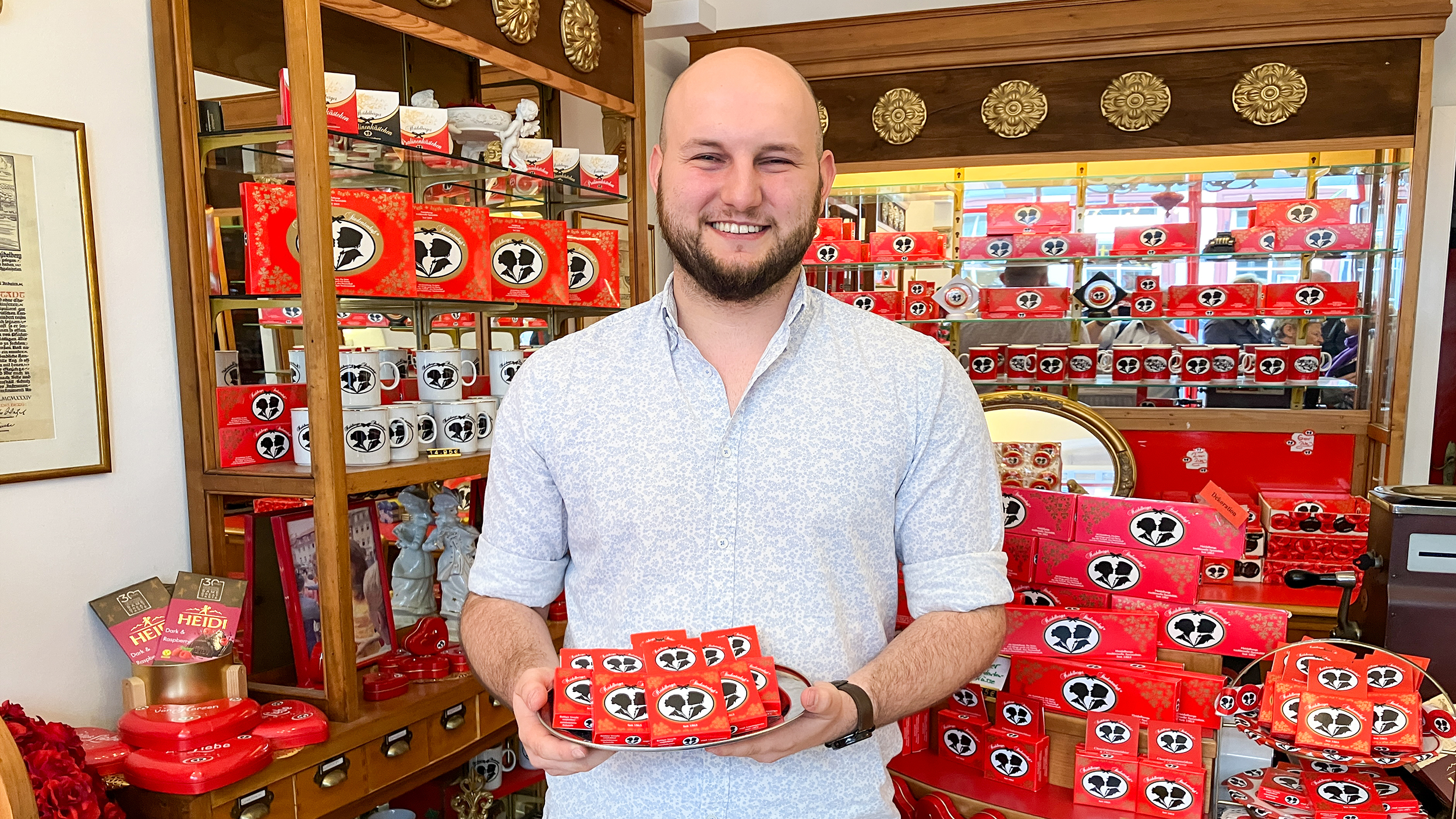 Verkaufer mit Studentenkuss-Schokotalern auf deinem Tablett steht im der Chocolaterie.