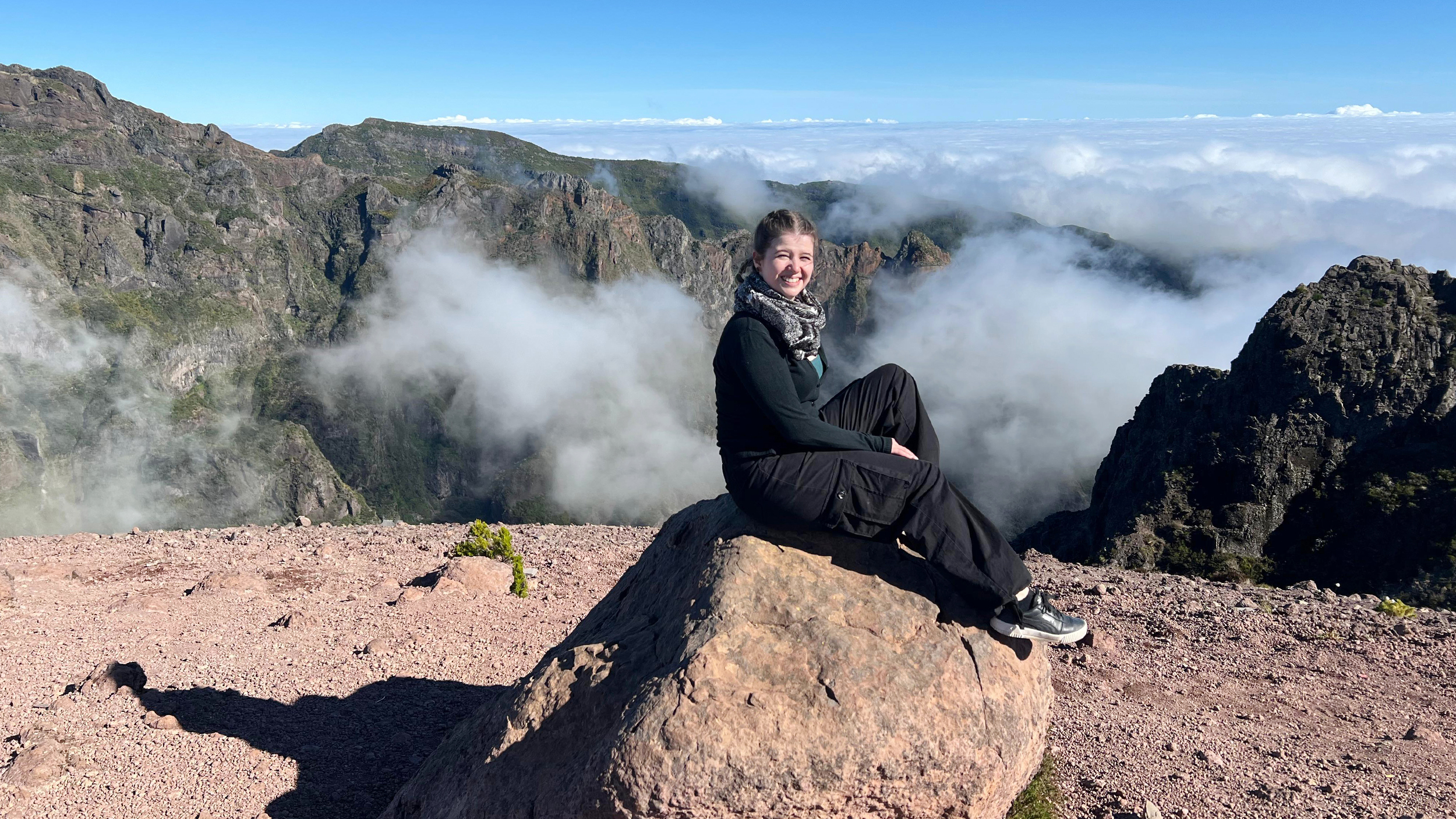 Redakteurin Verena Schauer auf einem Stein in Madeira. Hinter ihr ein Blick auf die Berge.