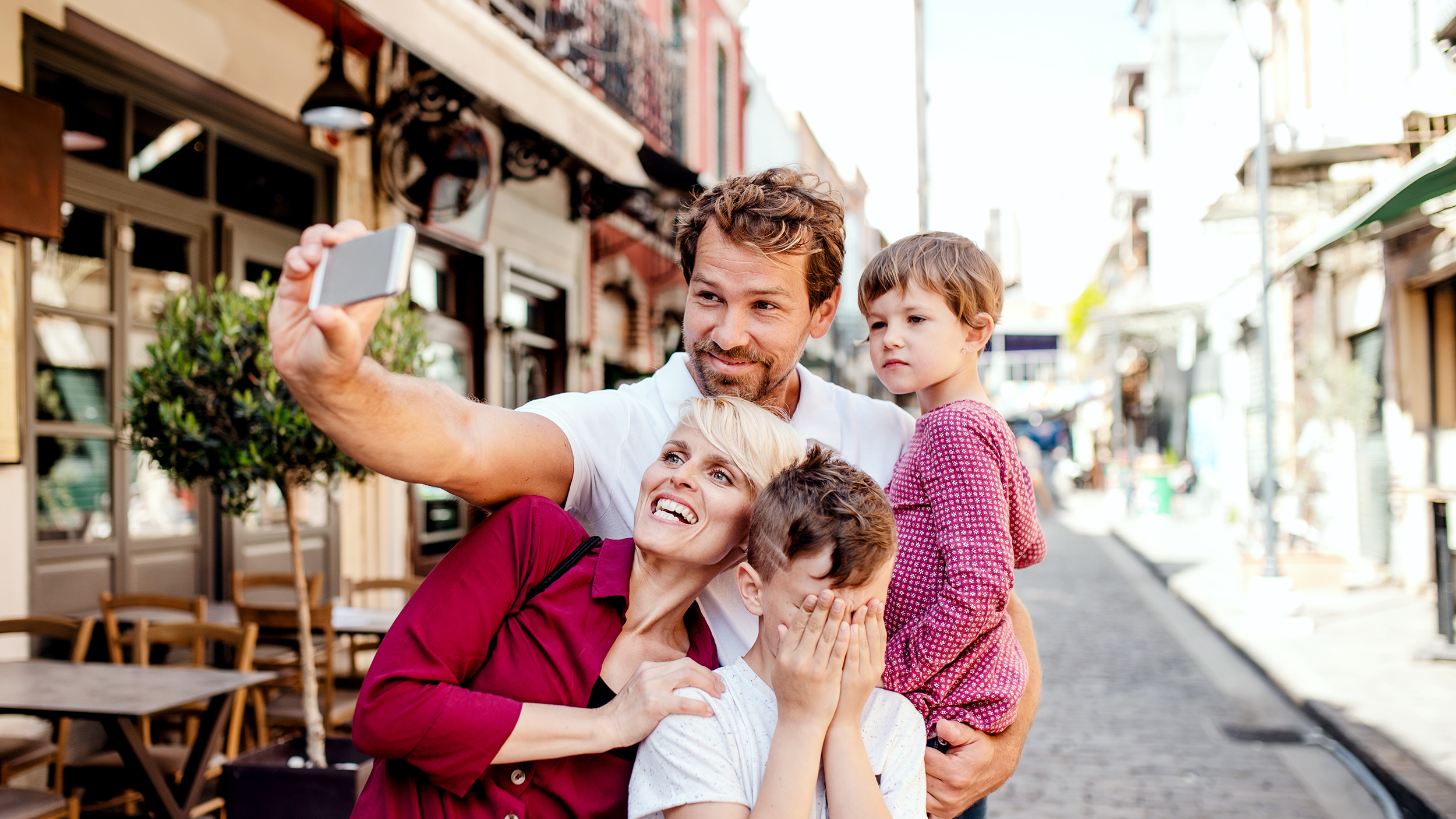 Eine Familie mit 2 Kindern macht gerade ein Selfie in einer Gasse.
