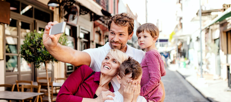 Eine Familie mit 2 Kindern macht gerade ein Selfie in einer Gasse.