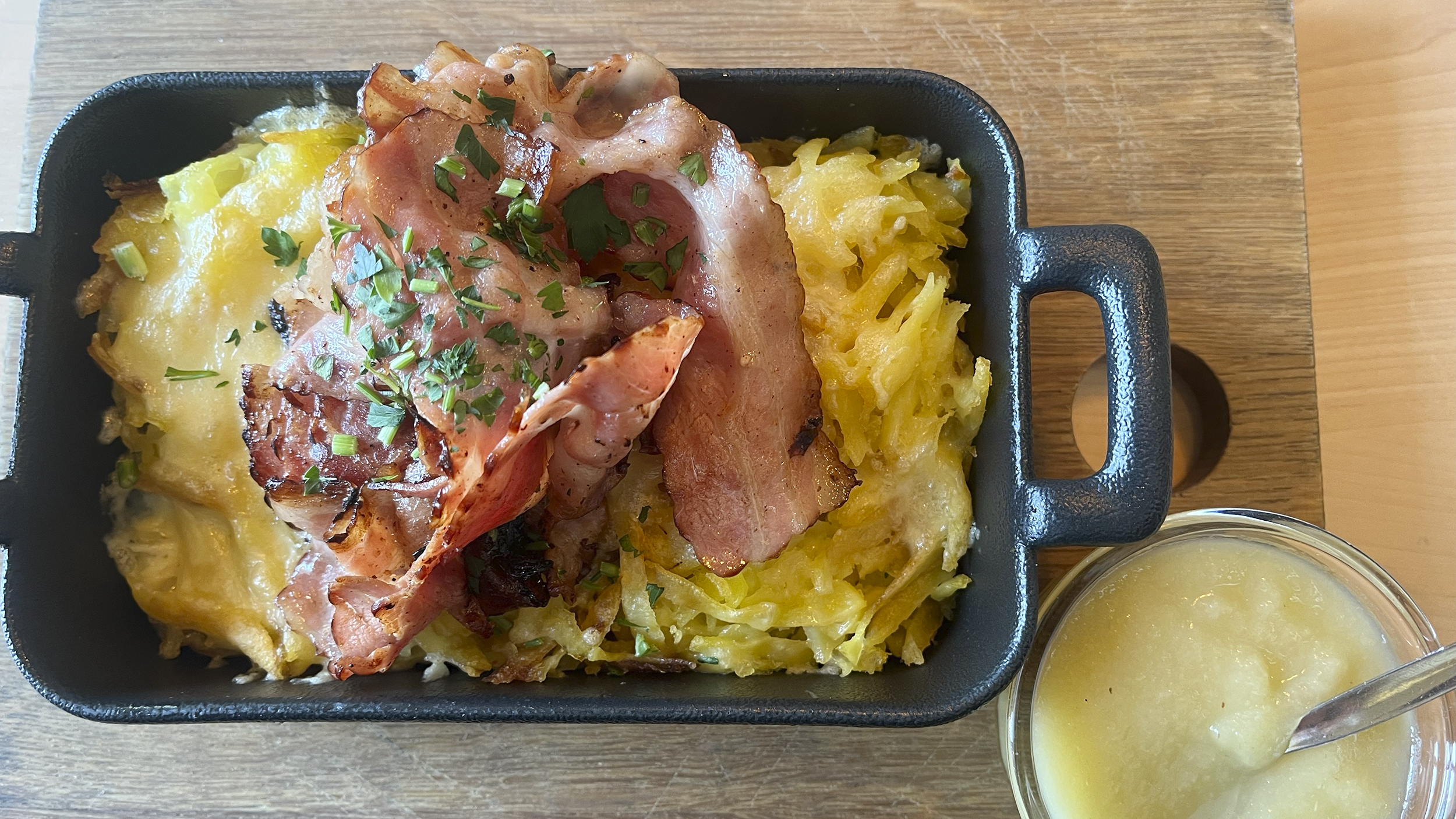 Berner Rösti mit Speck und Apfelmus in einer Eckpfanne.