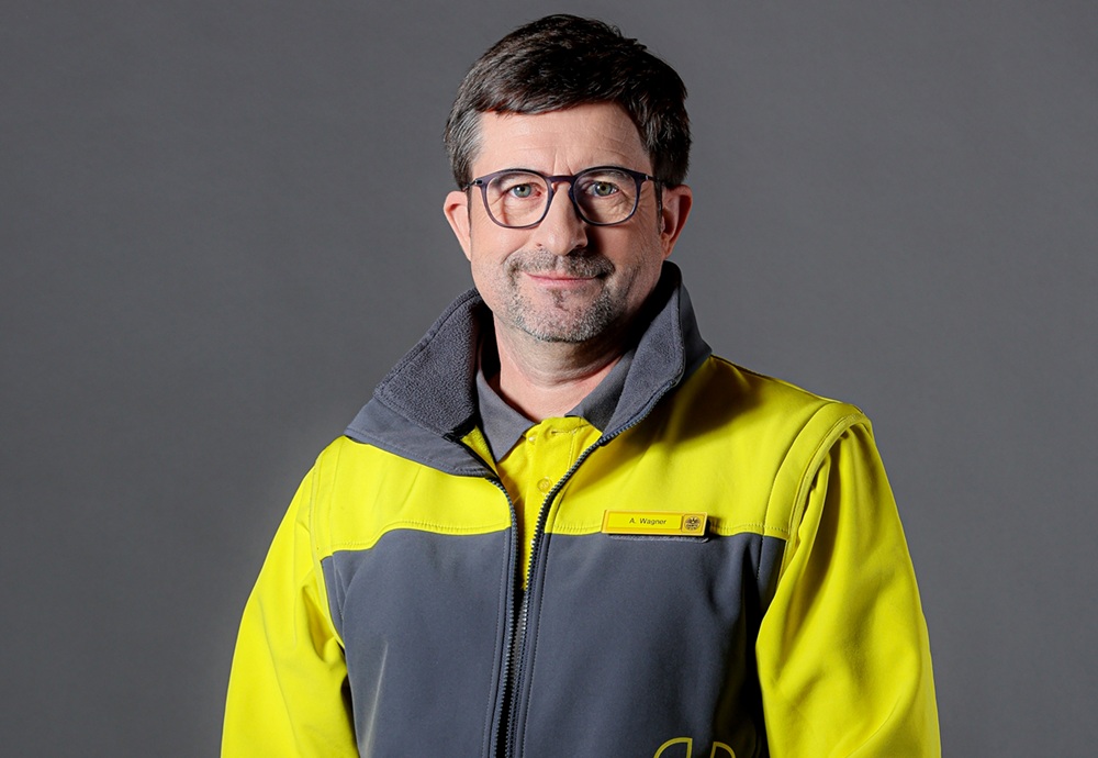 Ein Portraitfoto eines ÖAMTC-Mitarbeiters, der eine ÖAMTC-Jacke trägt, die gelb und grau ist.