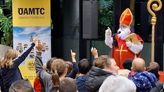 Das Foto zeigt einen Nikolaus, der vor vielen Kindern steht. Im Hintergrund ist ein ÖAMTC-Schild zu sehen.