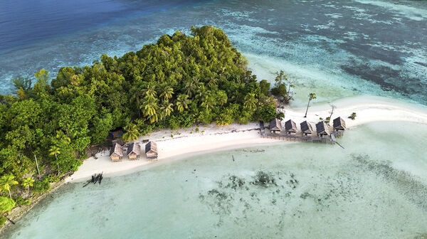 Luftaufnahme von Kri Island, Raja Ampat, Indonesien mit tropischem Strand, Meer und Überwasser-Bungalows