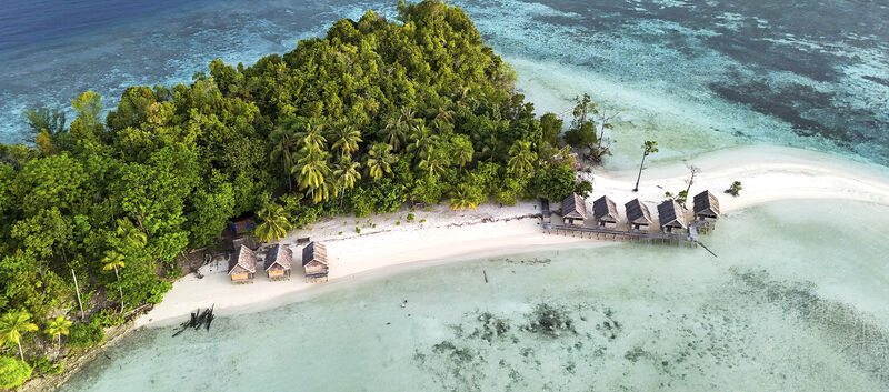 Luftaufnahme von Kri Island, Raja Ampat, Indonesien mit tropischem Strand, Meer und Überwasser-Bungalows