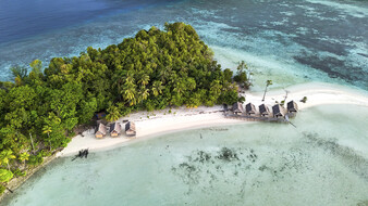 Luftaufnahme von Kri Island, Raja Ampat, Indonesien mit tropischem Strand, Meer und Überwasser-Bungalows