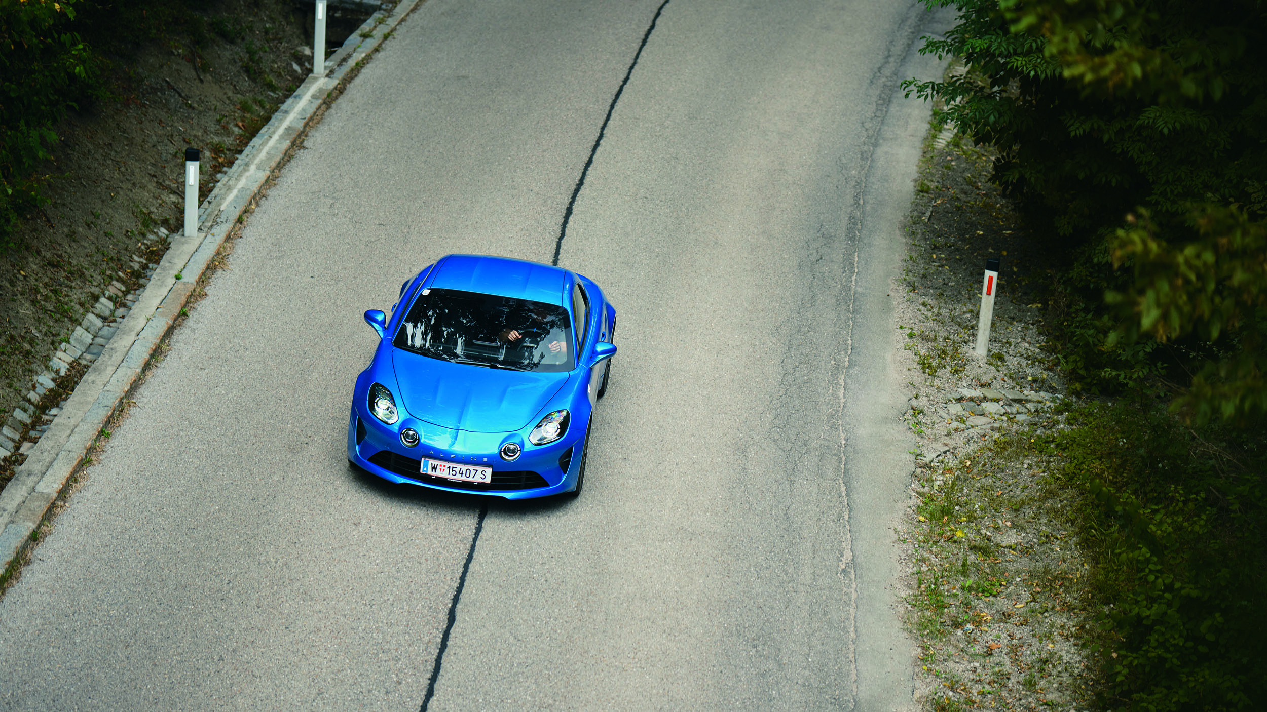 Eine blaue Alpine A110 fährt auf der Höhenstraße, von oben fotografiert