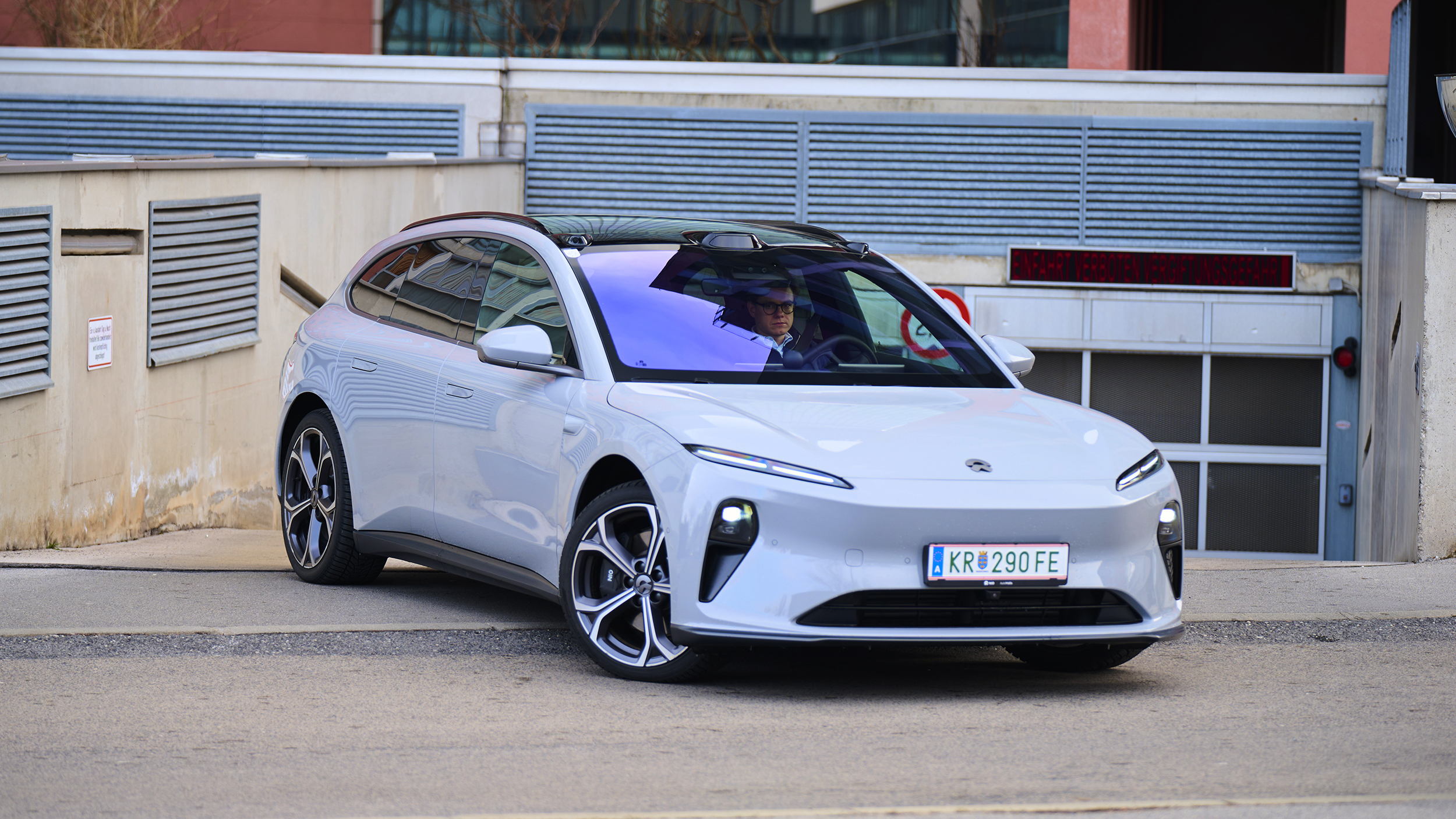 Ein hellblauer Nio ET5 Touring steht vor der Ausfahrt einer Tiefgarage.