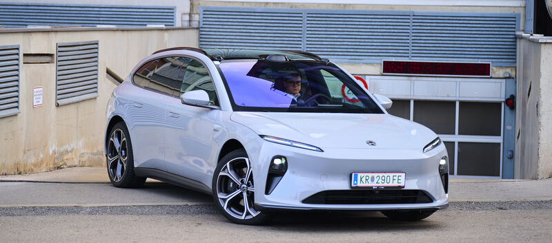 Ein hellblauer Nio ET5 Touring steht vor der Ausfahrt einer Tiefgarage.