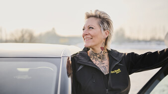 ÖAMTC Fahrtechnik Instruktorin Patricia lacht während sie aus einem Auto aussteigt.