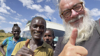 Ein weißer Tourist lacht mit den Afrikanern in die Kamera und macht ein Selfie.