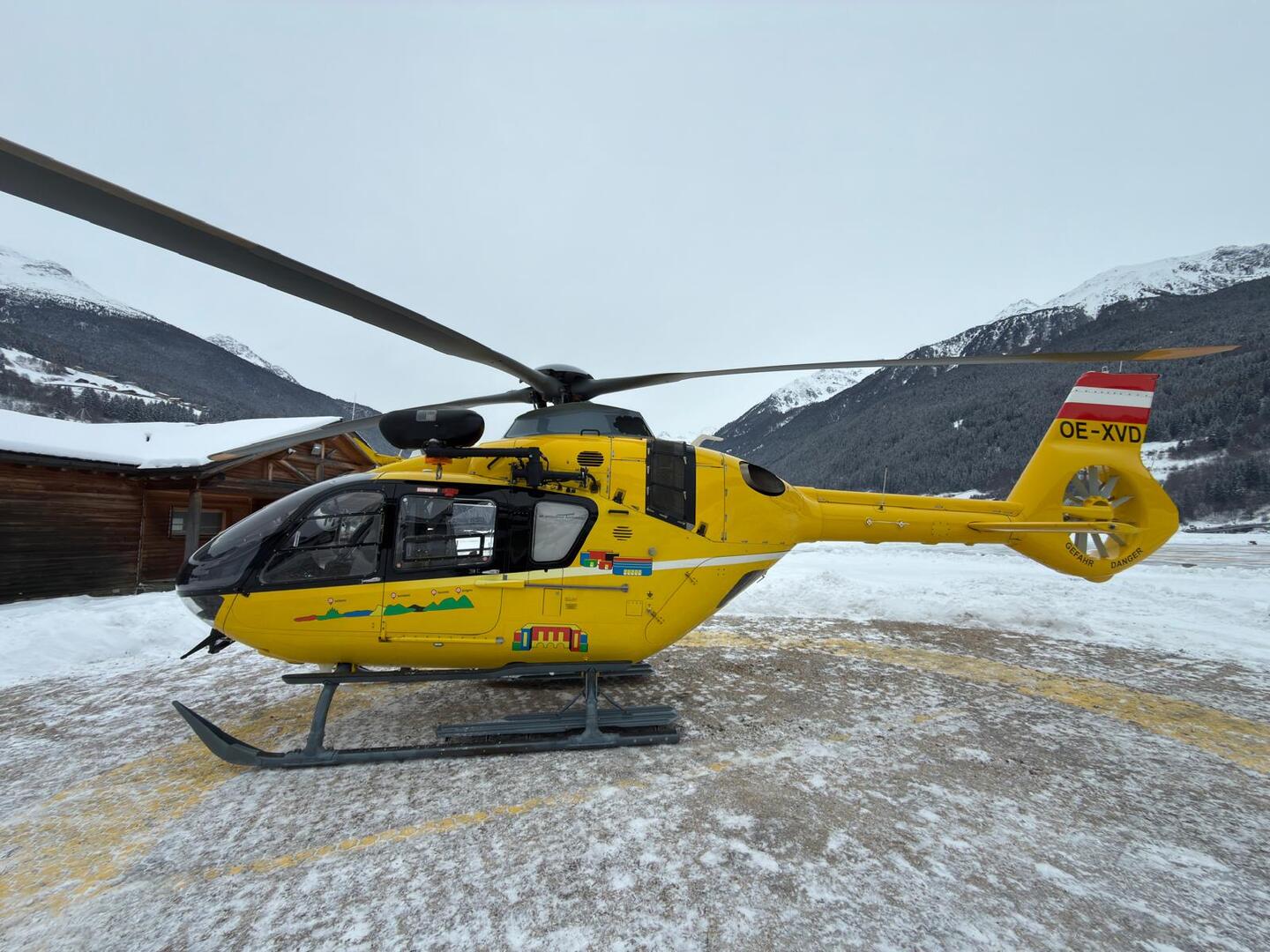 Ein gelber Notarzthubschrauber in winterlicher Landschaft.
