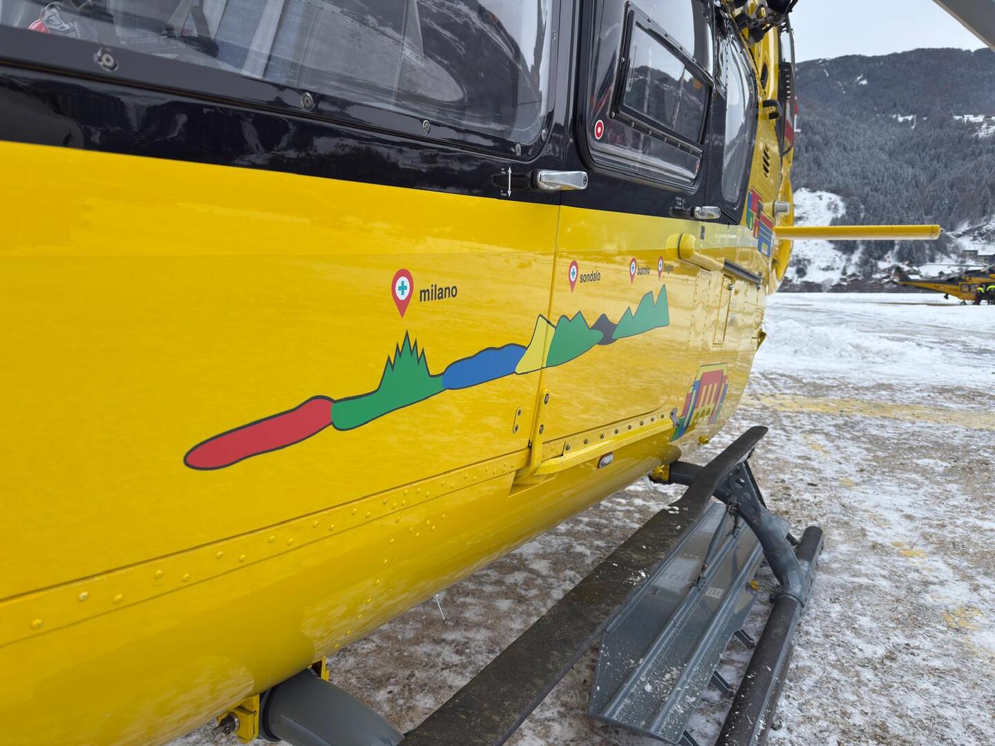 Ein gelber Notarzthubschrauber in winterlicher Landschaft.