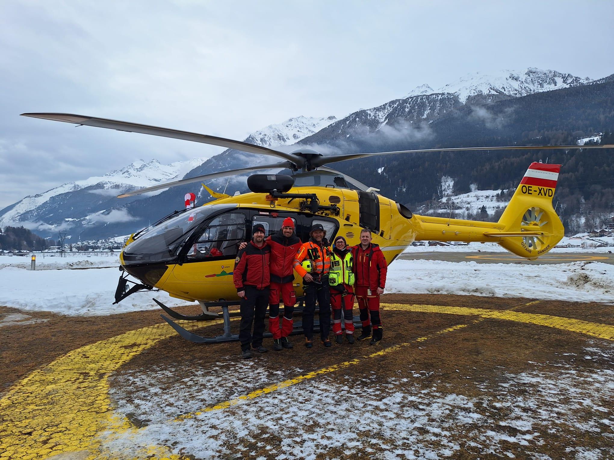 Das Foto zeigt einen gelben Notarzthubschrauber. Davor steht die Crew. 