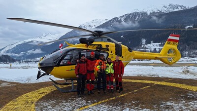 Das Foto zeigt einen gelben Notarzthubschrauber. Davor steht die Crew.