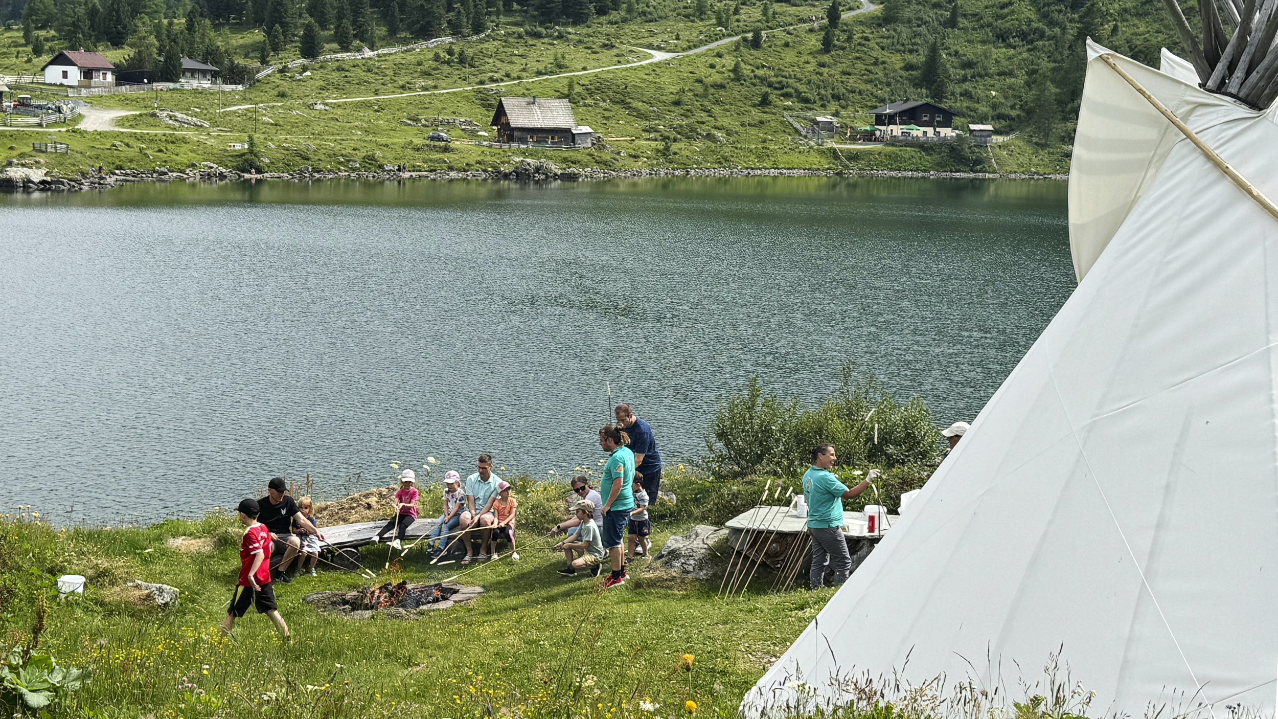 Steckerlbrot-Grillen mit vielen Kindern am See in den Bergen. 