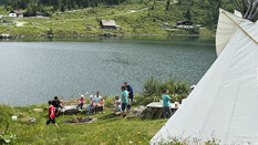 Steckerlbrot-Grillen mit vielen Kindern am See in den Bergen.