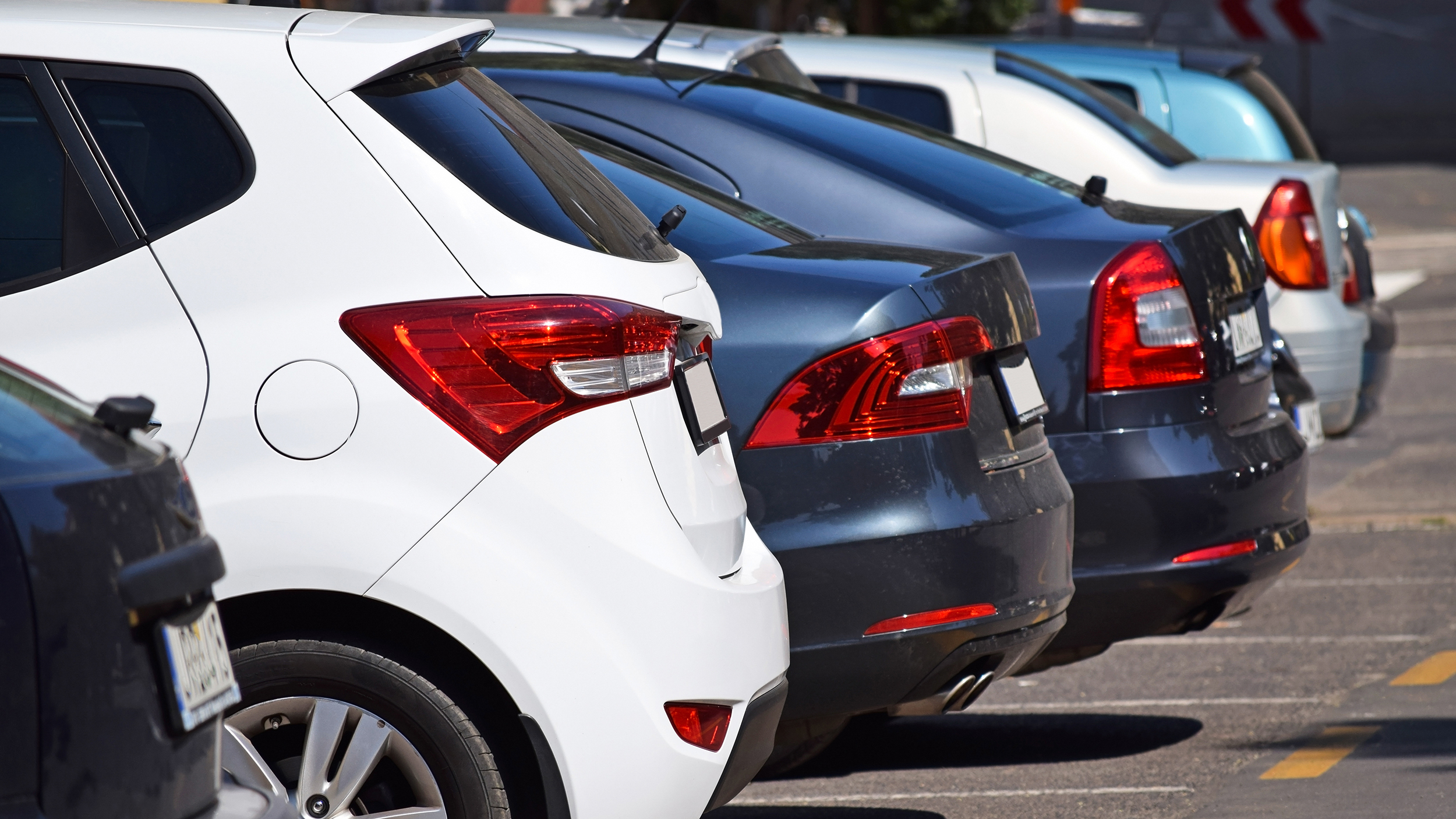 Die Hecks von mehreren nebeneinander stehenden Autos auf einem Parkplatz