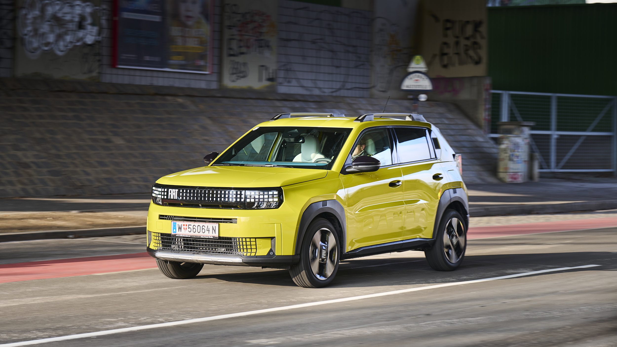 Ein gelber Fiat Grande Panda fährt durch die Stadt.