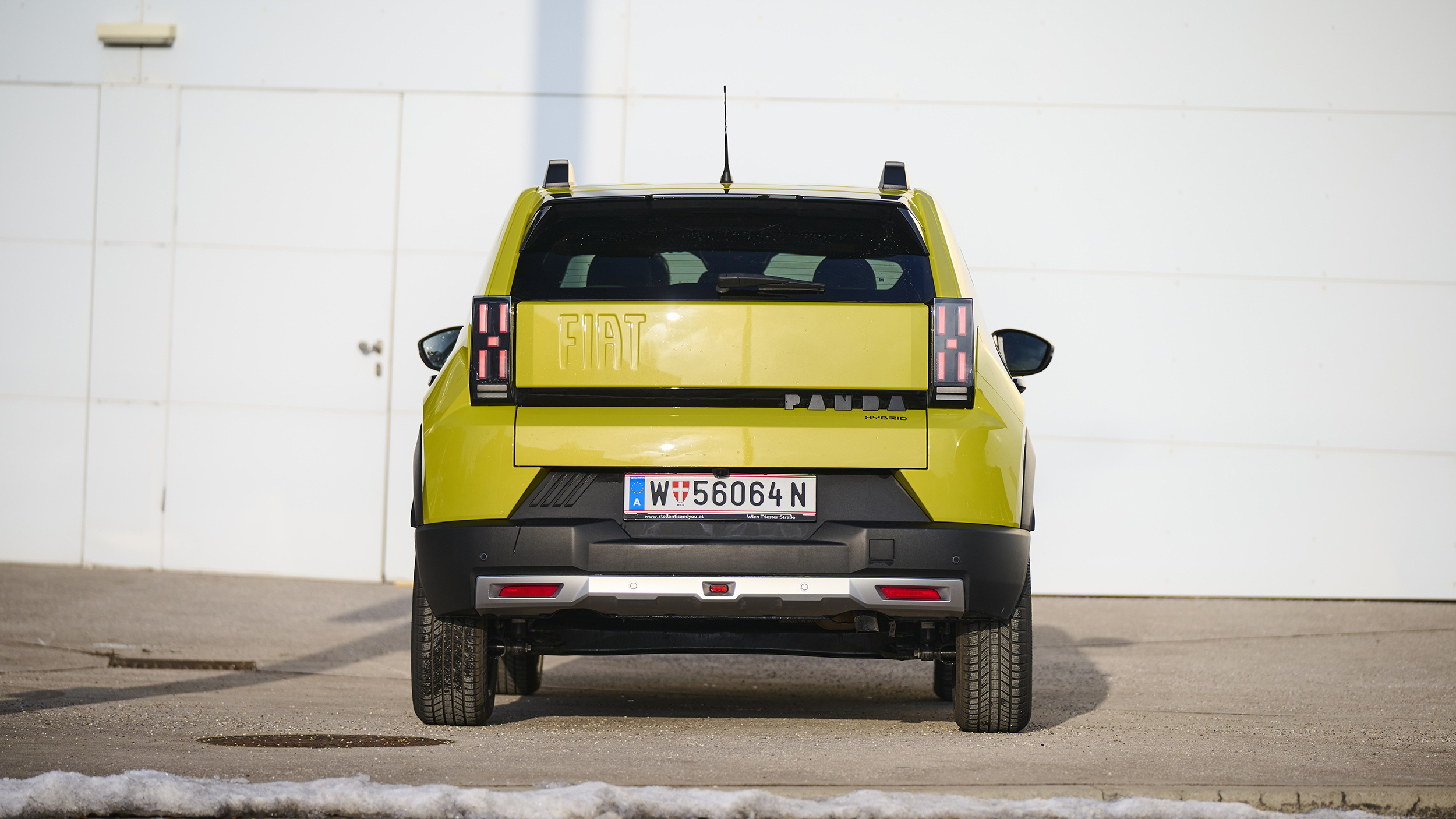 Ein gelber Fiat Grande Panda steht vor einer weißen Wand.