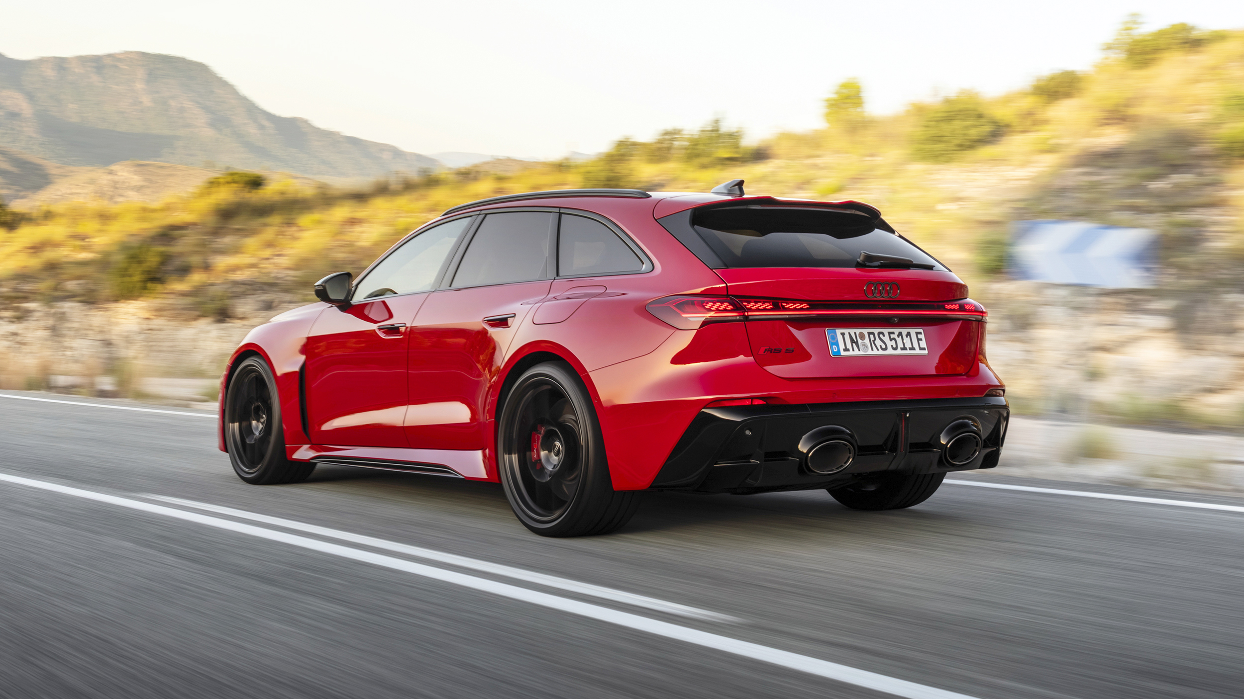 Ein roter Audi RS 5 Avant fährt durch eine Kurve einer Landstraße.
