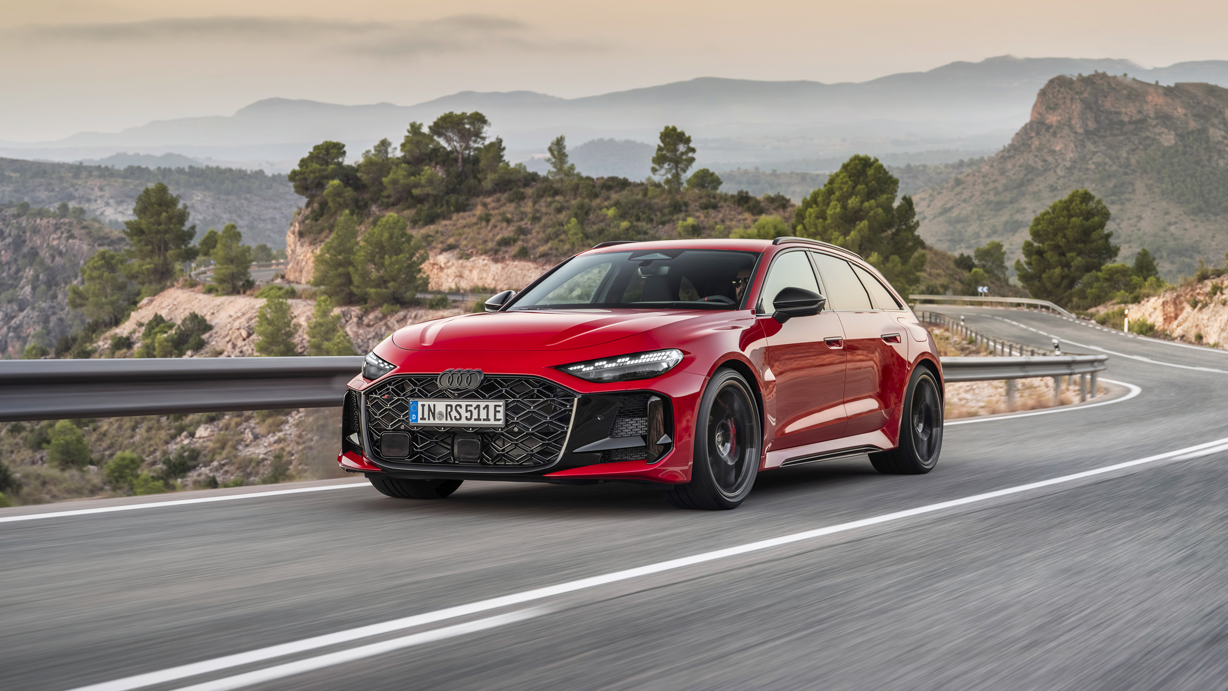 Eine roter Audi RS 5 Avant fährt über eine Landstraße.