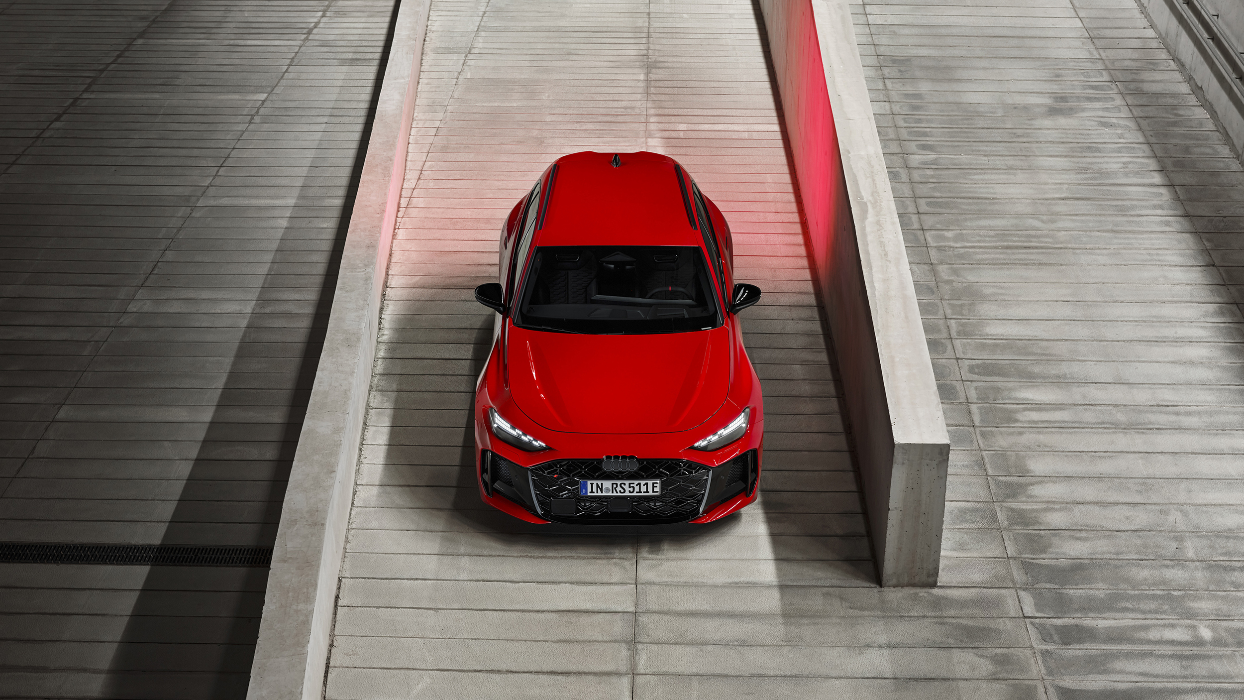 Eine roter Audi RS 5 Avant steht von oben fotografiert zwischen zwei Steinmauern.