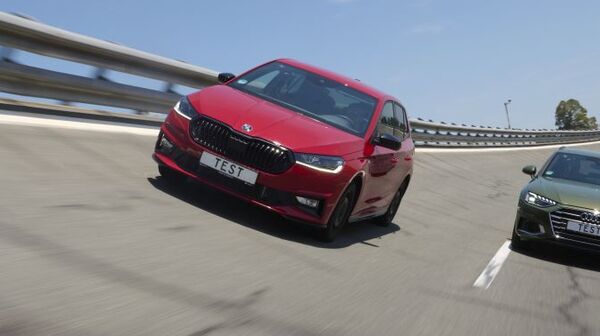 Ein rotes und ein grünes Auto fahren nebeneinander auf einer Teststrecke.