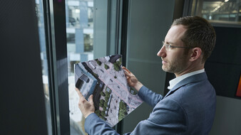 Verkehrsexperte Matthias Nagler steht vor einem Fenster und hält eine Karte in der Hand.