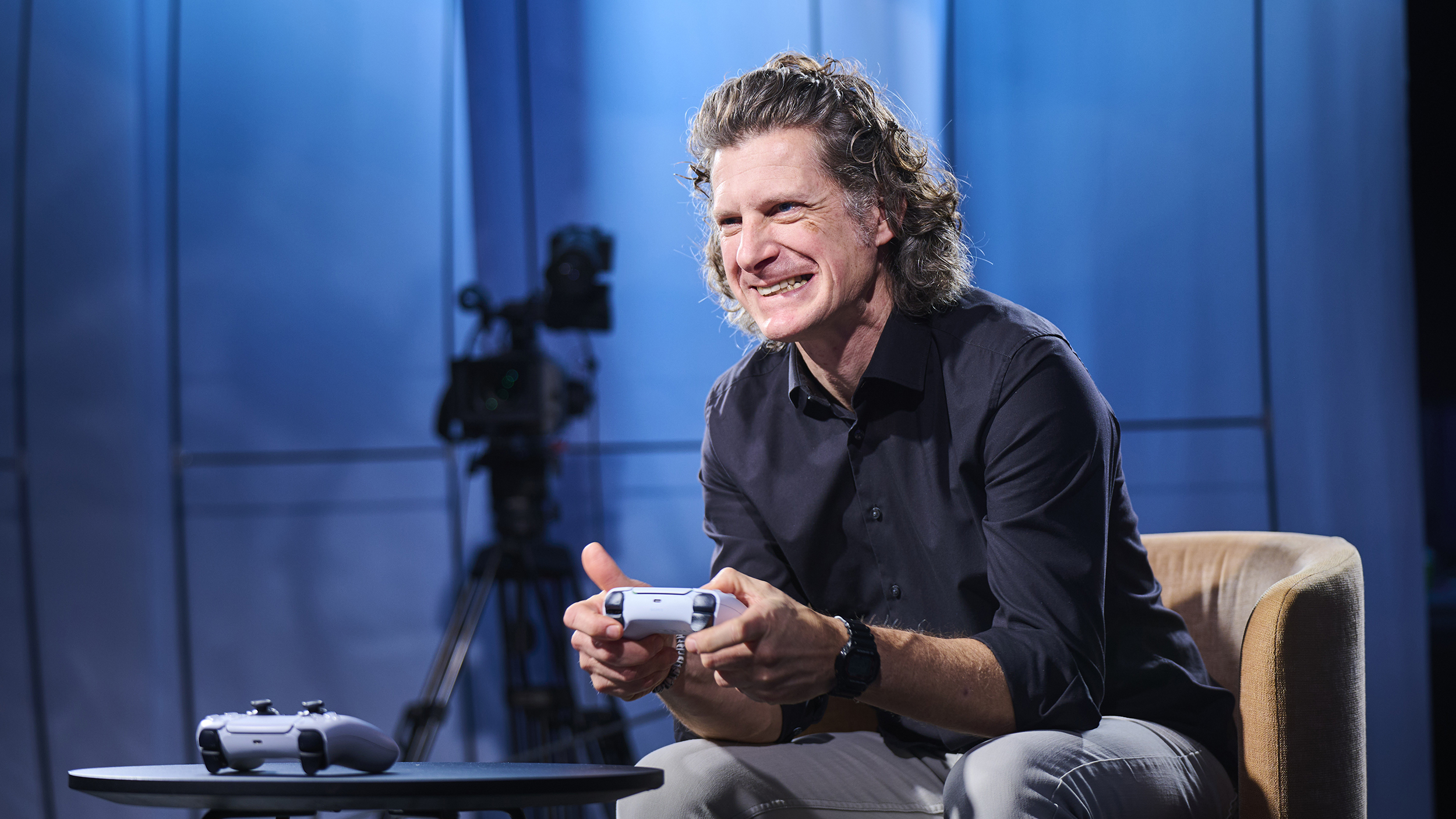 Redakteur Alex Fischer sitzt mit PS5 Controller und spielt. Er lacht. 