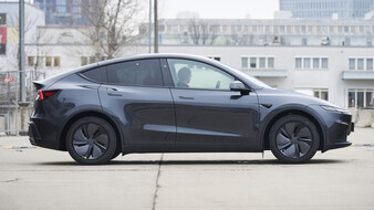 Die Seitenansicht eines grauen Tesla Model Y, das auf der Straße steht.