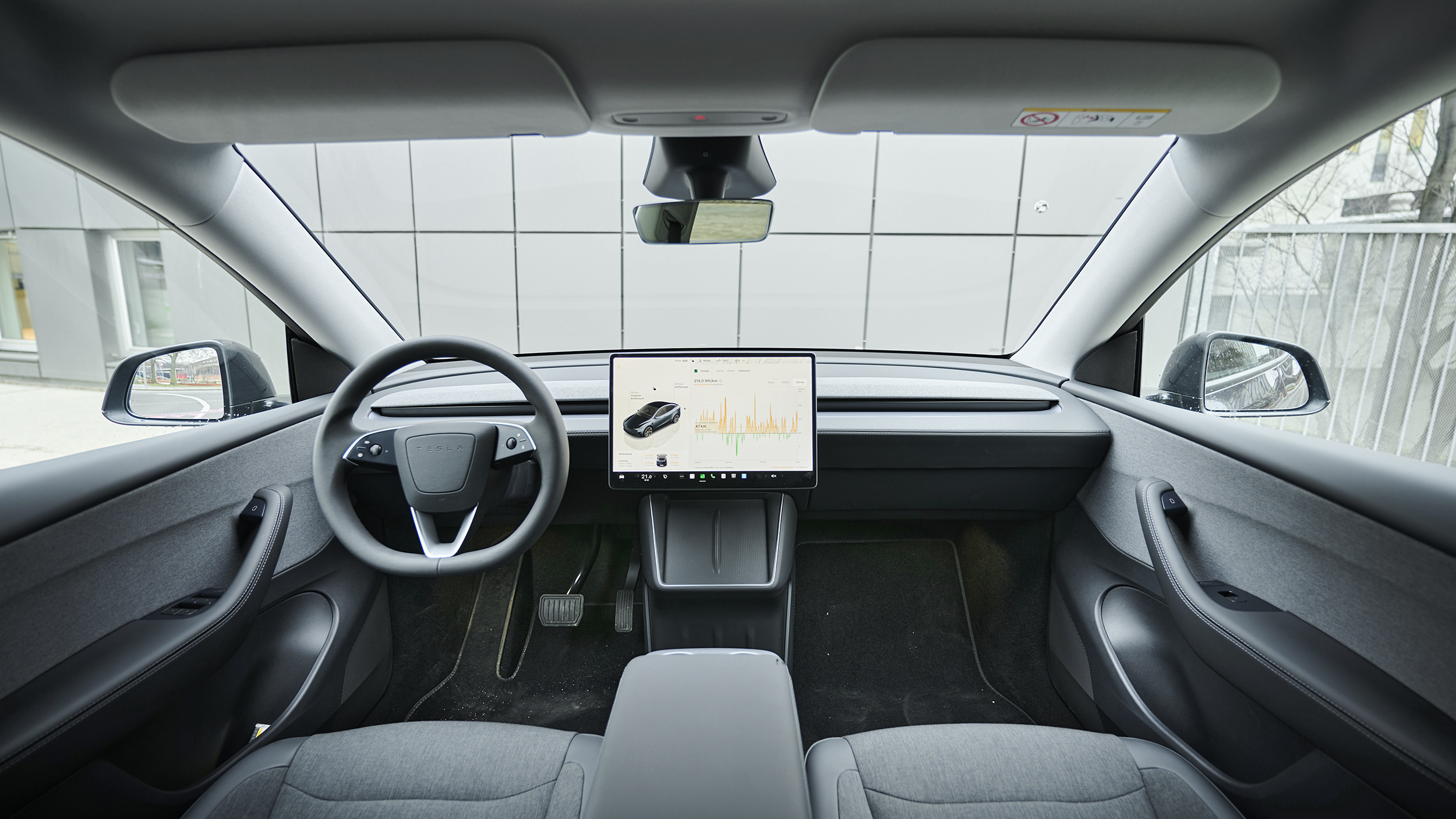 Innenraum eines Tesla Model Y mit großem Zentral-Touchscreen.