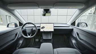 Innenraum eines Tesla Model Y mit großem Zentral-Touchscreen.