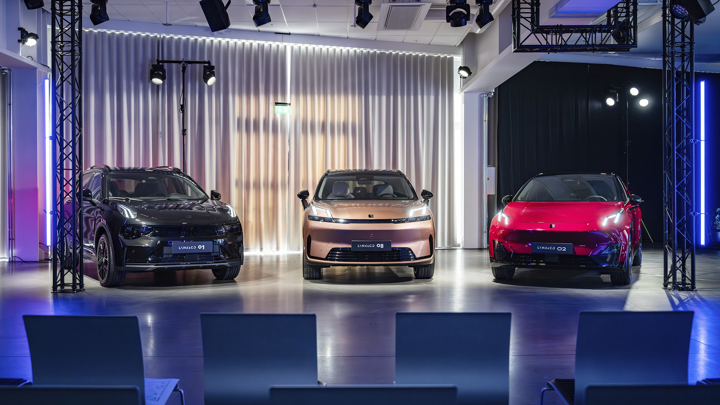 Drei Fahrzeuge der Marke Lynk & Co stehen auf einer Bühne im Scheinwerferlicht.