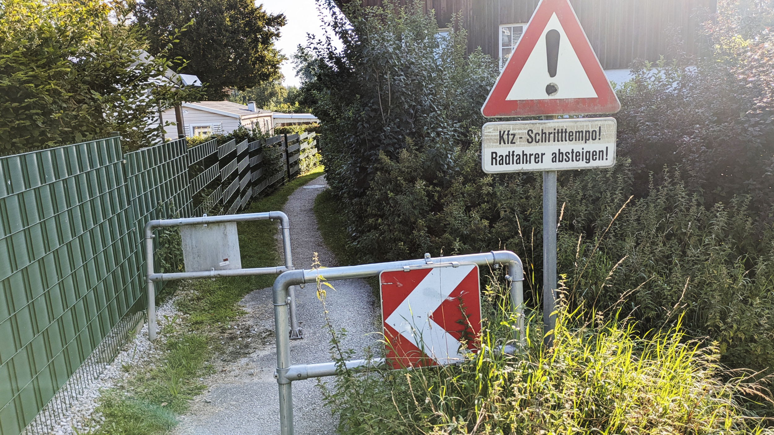 Ein Hindernis auf einem sehr schmalen Radweg, davor ein Verkehrszeichen, dass Kraftfahrzeuge im Schrittempo die Engstelle passieren müssen.