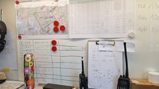 Auf dem Bild sieht man einen unaufgeräumten Arbeitstisch mit zwei Funkgeräten.