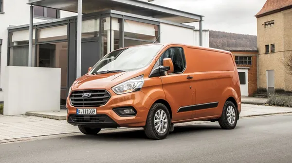 Das Bild zeigt ein orangenes Nutzfahrzeug vor einem Haus.