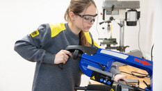 Es ist eine junge Frau zu sehen, die an einem Gerät arbeitet.