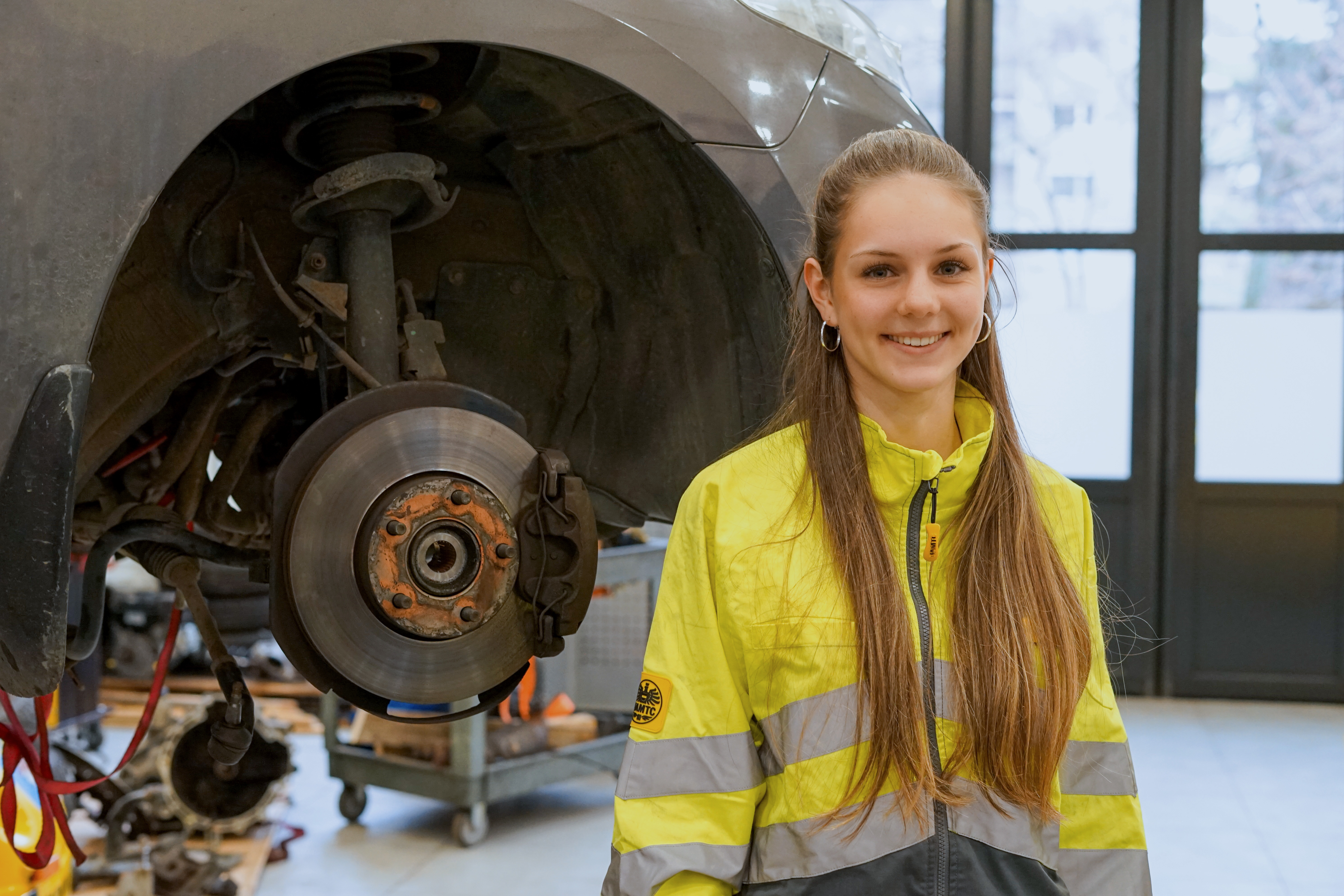 Es ist eine junge Frau zu sehen, die in einer Werkstatt steht.