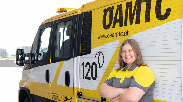 Es ist eine Frau in ÖAMTC-Kleidung zu sehen. Sie lehnt an einem Pannenfahrzeug.