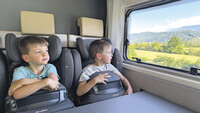 Zwillinge sitzen in ihren Kindersitzen nebeneinander.